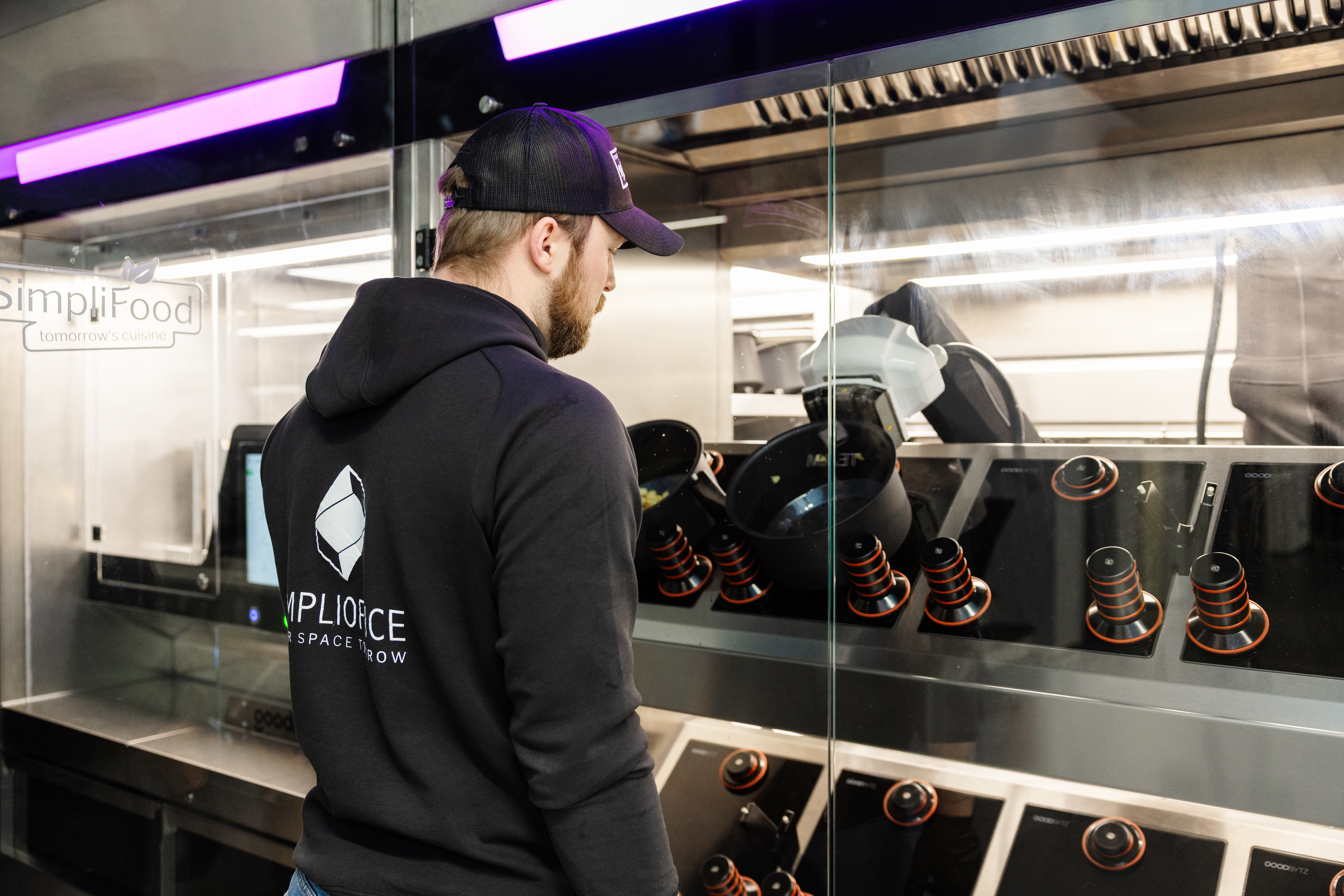 Mitarbeiter von SimpliOffice schaut, wie die Töpfe vom SimpliFood Kochroboter arbeiten